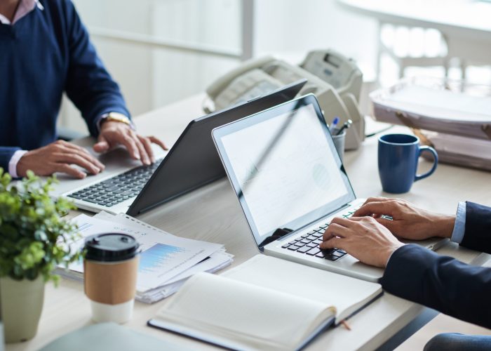 Cropped image of business people working on laptops in office